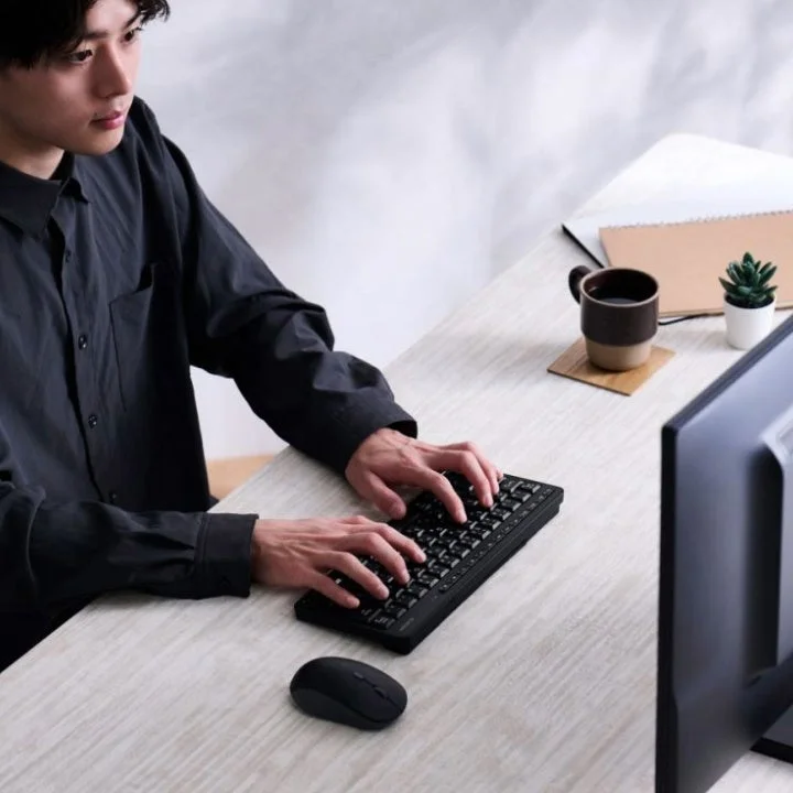 デスクでパソコンに向かいキーボードを操作する男性