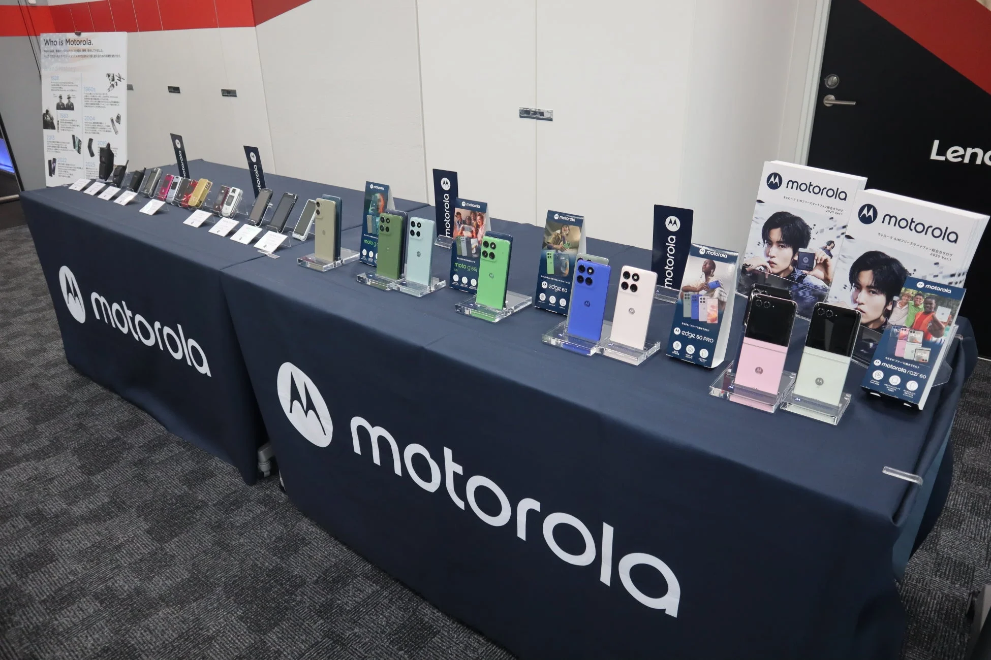 Motorolaの製品展示ブースで、様々な色のスマートフォンが並べられたテーブルが写っています。