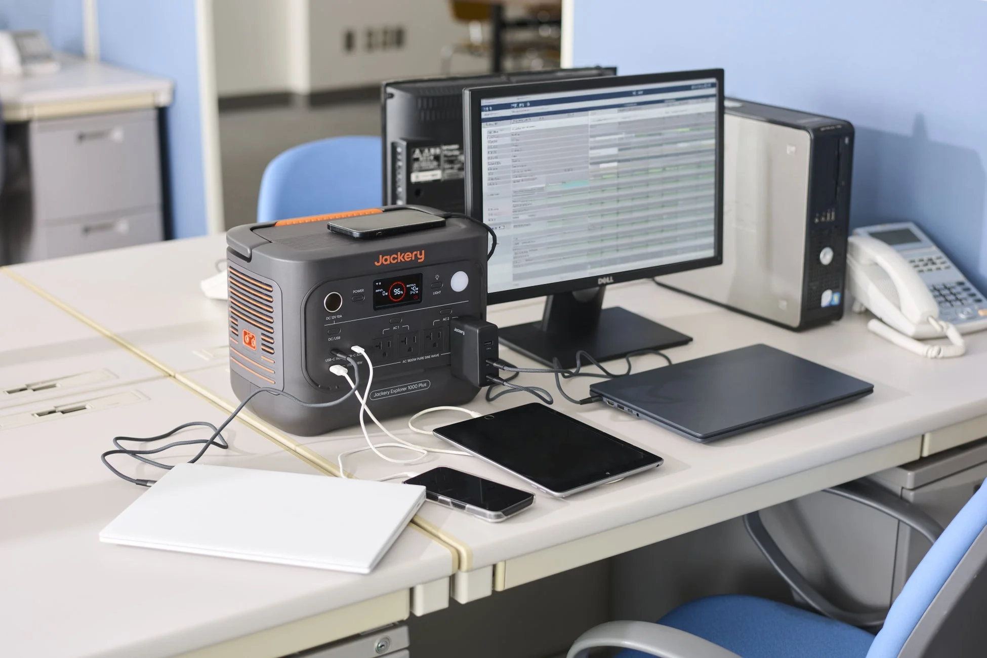 オフィスデスクでJackeryのポータブル電源が複数の電子機器に給電している様子です。