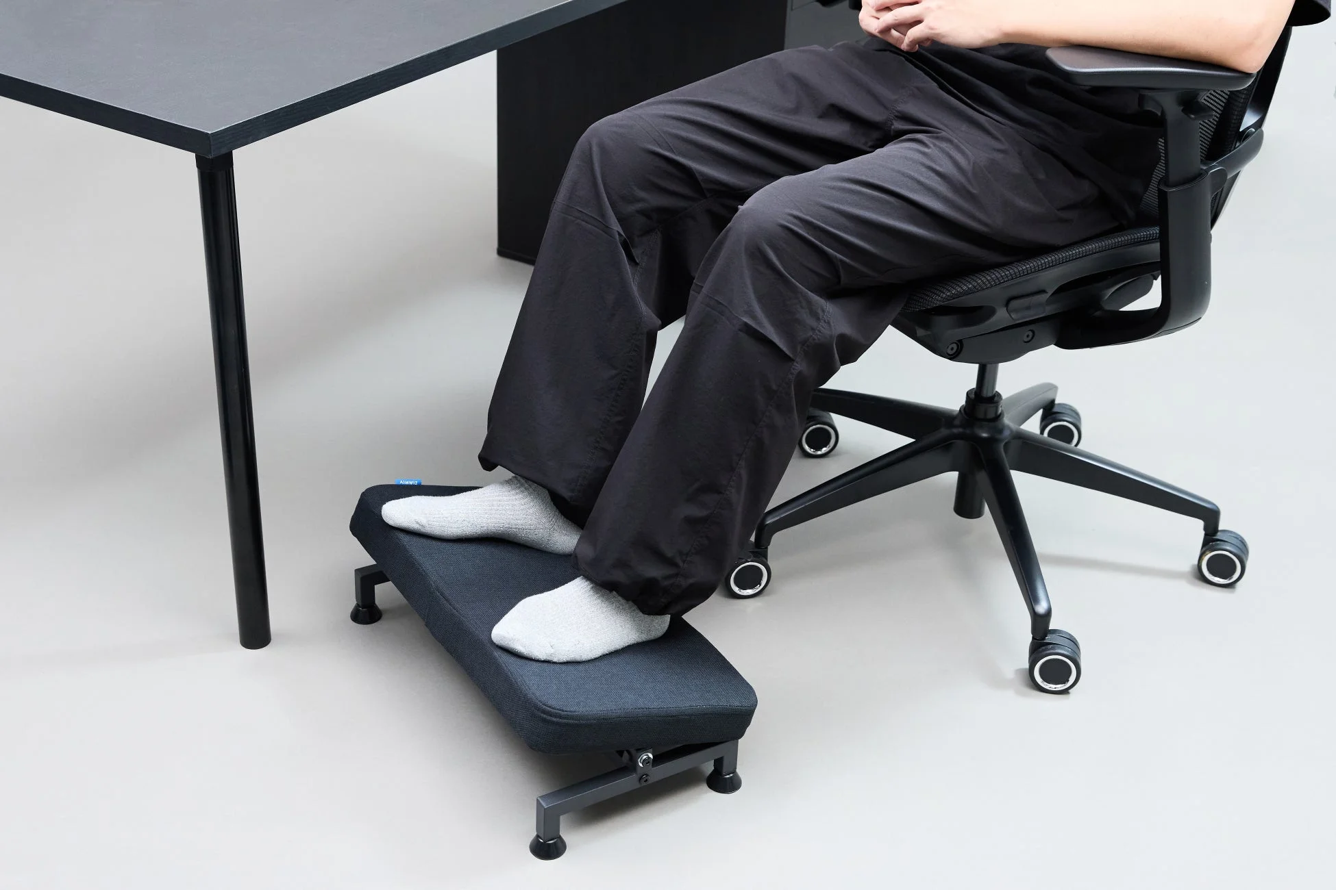 オフィスチェアに座った人物がフットレストに足を乗せてリラックスしている様子