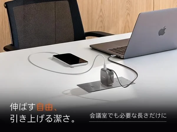 白のデスクで、ノートパソコンとスマートフォンが充電器に接続され、ケーブルが整理されている様子