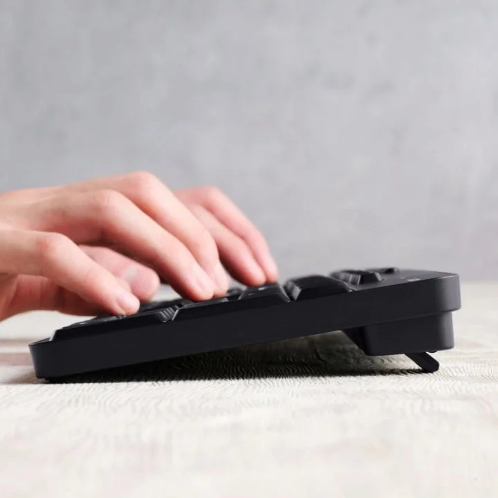 黒いキーボードをタイピングする人物の手元