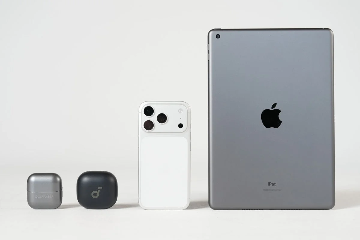 COMPASS+とAnkerの小型ケース、白いスマートフォン、iPadが並べられ、電子機器のサイズ比較をしている