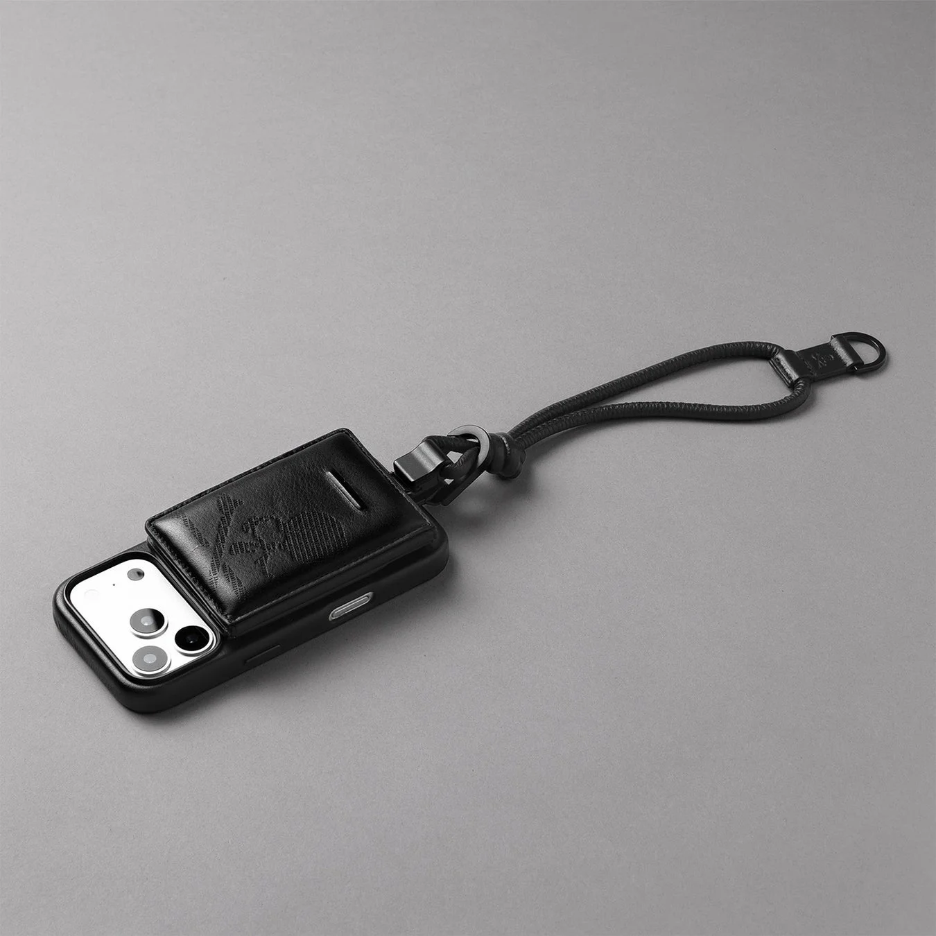 黒いスマートフォンケースにカードホルダーとリストストラップが一体となったデザイン