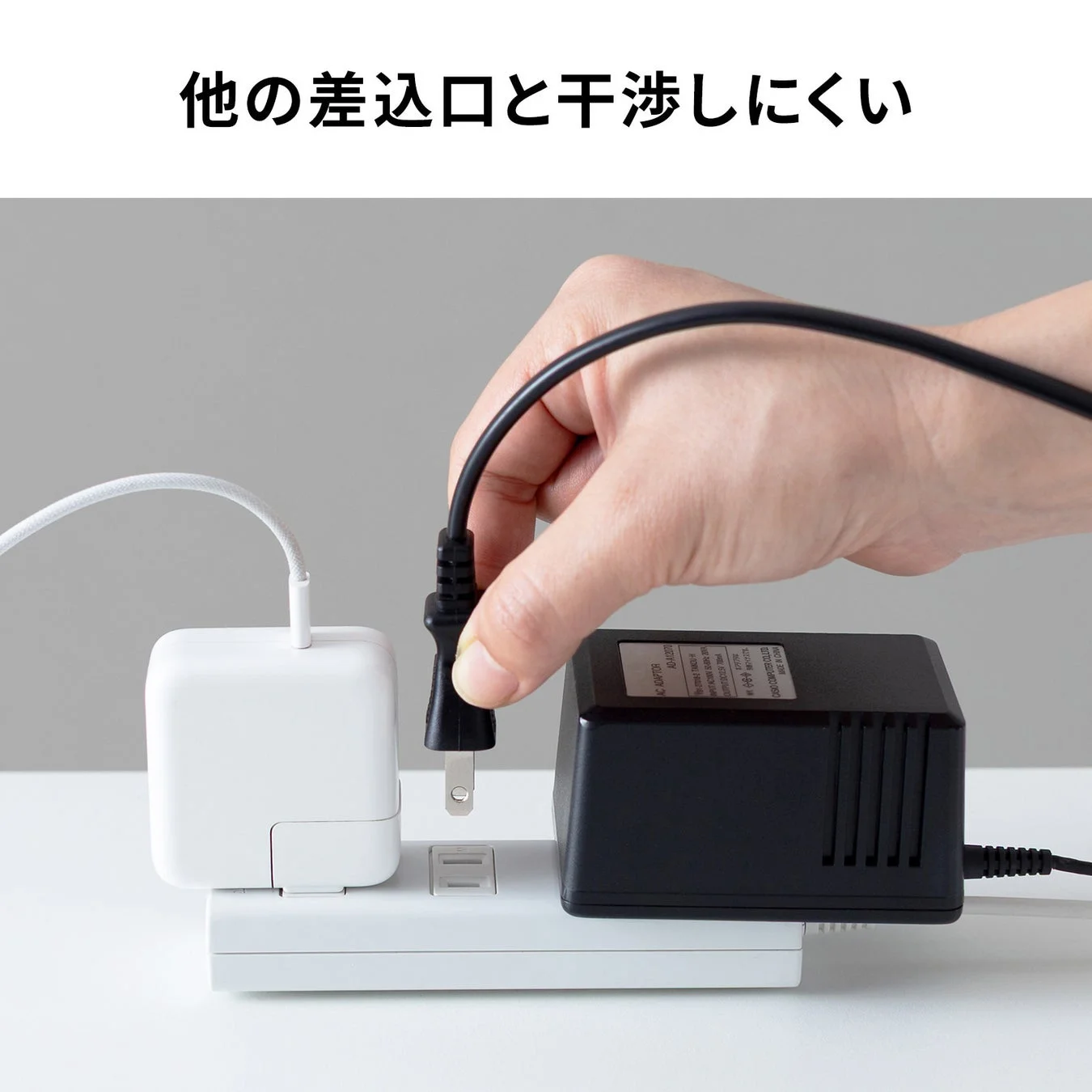 電源タップに電源コードを差し込む様子が写っており、大型のACアダプターが隣接しても他の差し込み口と干渉しにくい設計