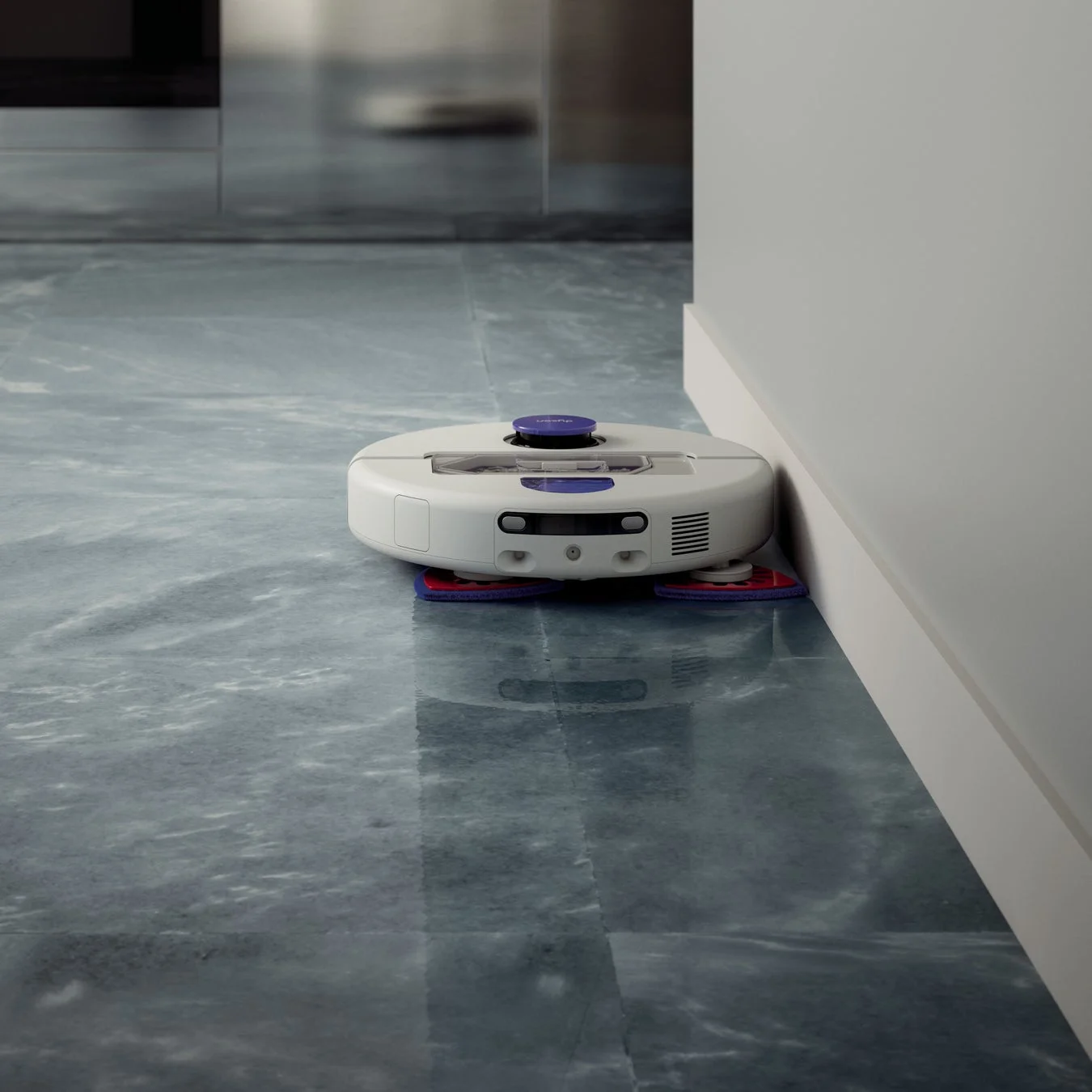 Dyson製の白いロボットモップが、濡れたような光沢のあるグレーの床を清掃している様子