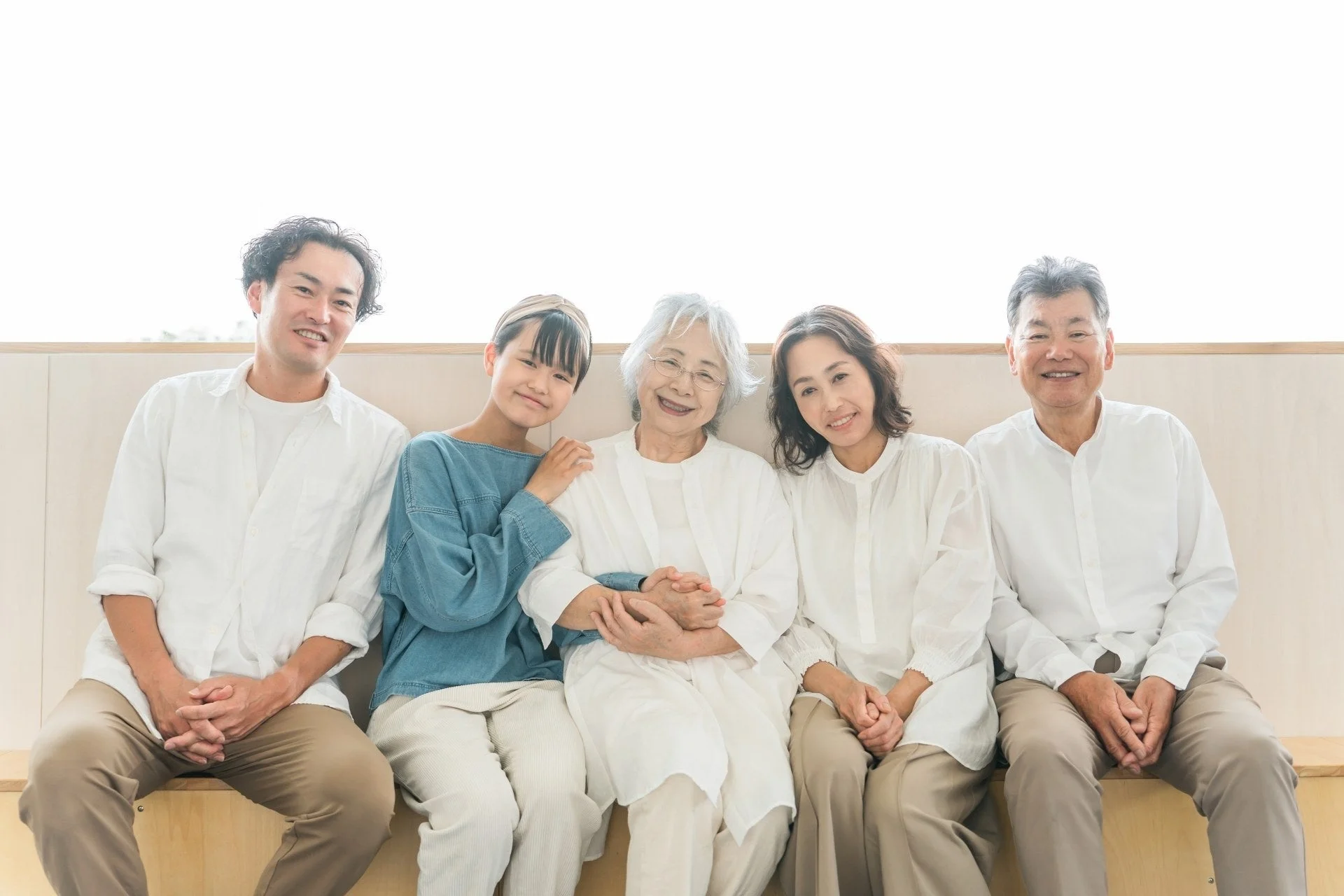 三世代の家族と思われる5人が、明るい空間で笑顔で座っている集合写真です。皆がリラックスした表情で、和やかな雰囲気が伝わってきます。