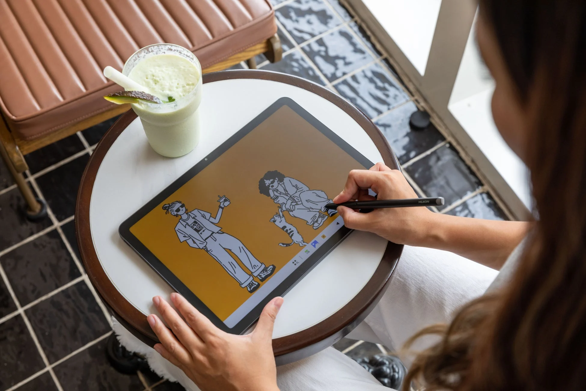 カフェでタブレットを使ってデジタルイラストを描く女性