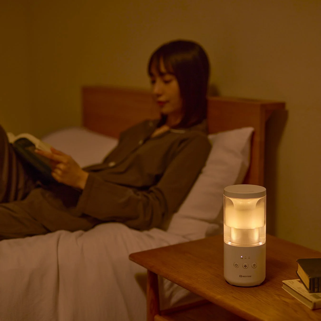 夜の寝室で女性がベッドに横たわり本を読んでいます