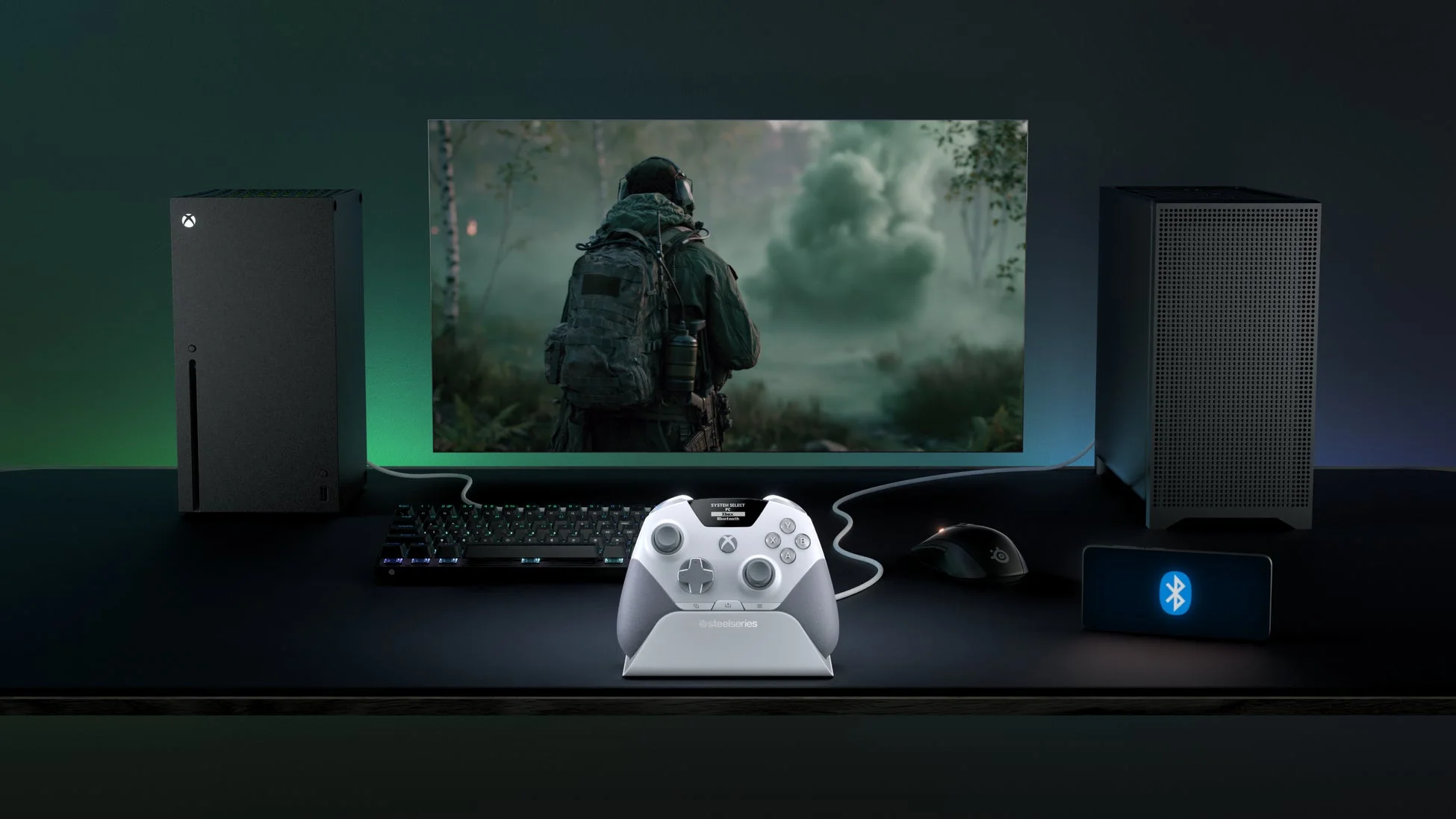 暗い部屋のゲーミングデスクに設置されたXbox Series XとPC、モニター、コントローラーなどのゲーミングセットアップ。モニターにはFPSゲームのシーンが映し出されています。